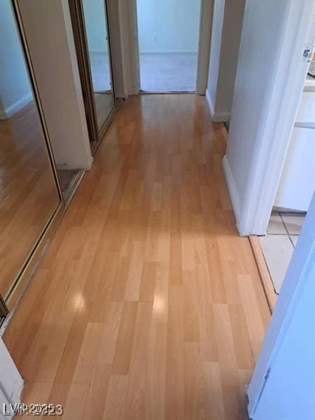 hallway featuring light wood-style flooring and baseboards