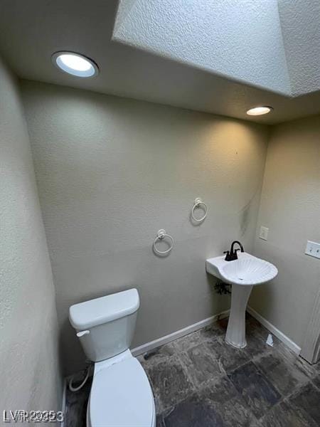 bathroom with baseboards and toilet