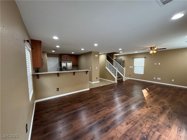 unfurnished living room with baseboards, stairway, wood finished floors, and recessed lighting