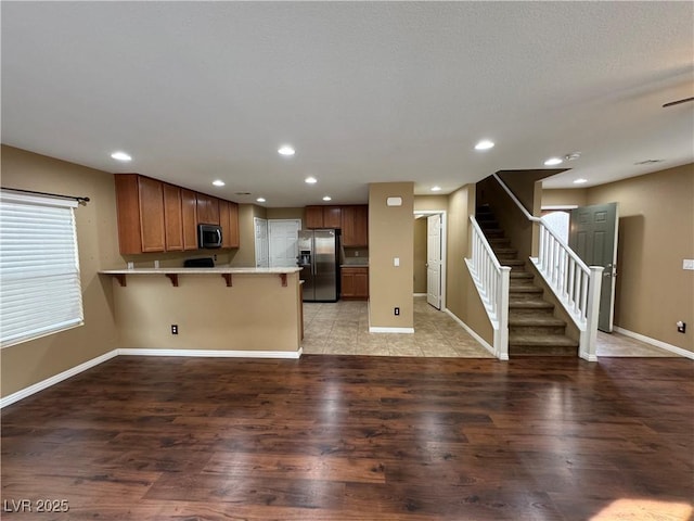 kitchen with a breakfast bar, light countertops, appliances with stainless steel finishes, light wood-style floors, and a peninsula