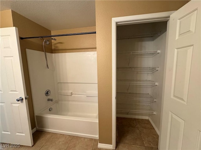 full bathroom with bathtub / shower combination, a textured ceiling, baseboards, and tile patterned floors