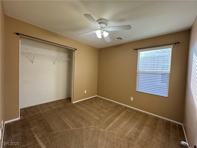 unfurnished bedroom with baseboards, visible vents, a ceiling fan, carpet flooring, and a closet