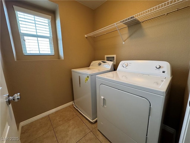 clothes washing area with washer and dryer, laundry area, baseboards, and light tile patterned floors