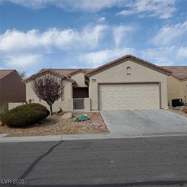 ranch-style home featuring concrete driveway, a tile roof, an attached garage, and stucco siding