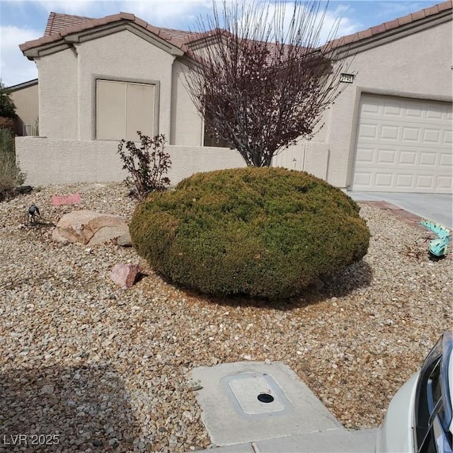 view of front of property featuring a garage, a tiled roof, and stucco siding