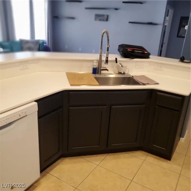 kitchen with light tile patterned floors, light countertops, white dishwasher, and a sink