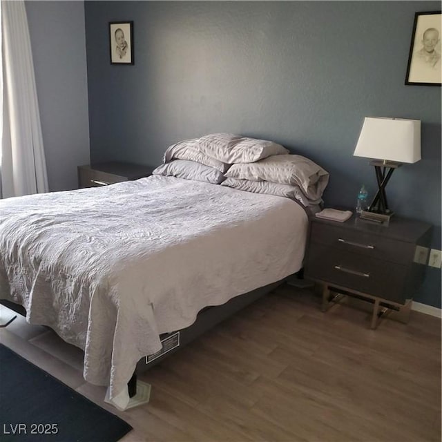 bedroom with wood finished floors and baseboards