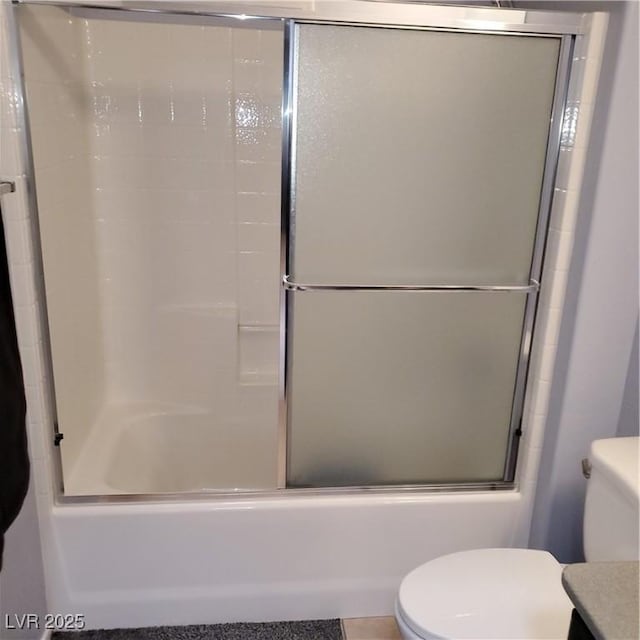 bathroom with combined bath / shower with glass door and toilet