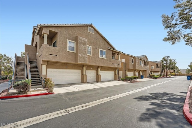 view of front of property featuring a residential view, stucco siding, stairs, and a garage