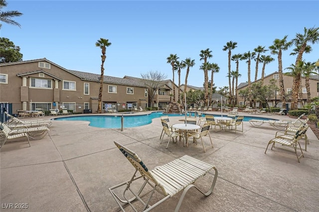 community pool with a patio area, fence, and a residential view