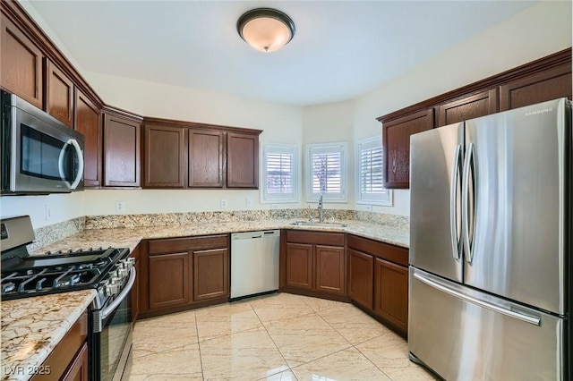 kitchen with a sink, light stone countertops, marble finish floor, and stainless steel appliances