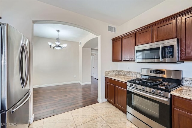 kitchen featuring visible vents, a notable chandelier, light stone counters, arched walkways, and appliances with stainless steel finishes