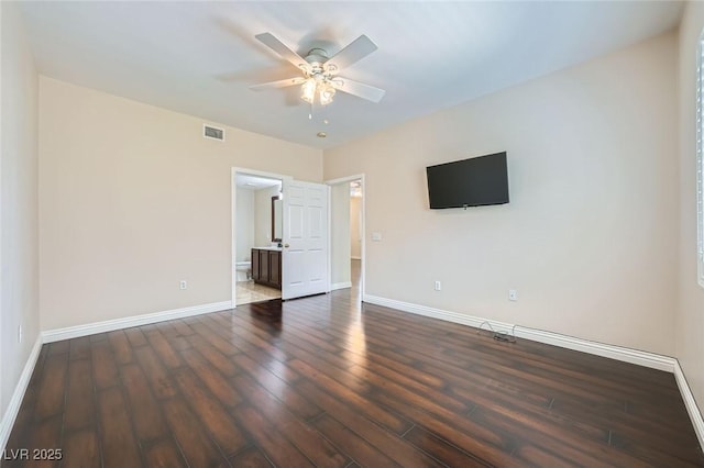 unfurnished bedroom featuring dark wood finished floors, baseboards, visible vents, and ensuite bathroom