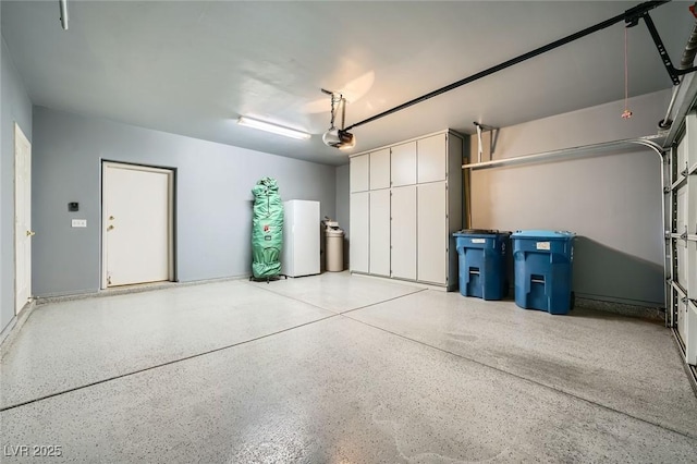 garage with a garage door opener and freestanding refrigerator