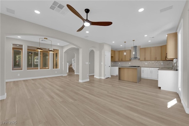 unfurnished living room featuring visible vents, arched walkways, light wood-type flooring, a sink, and recessed lighting