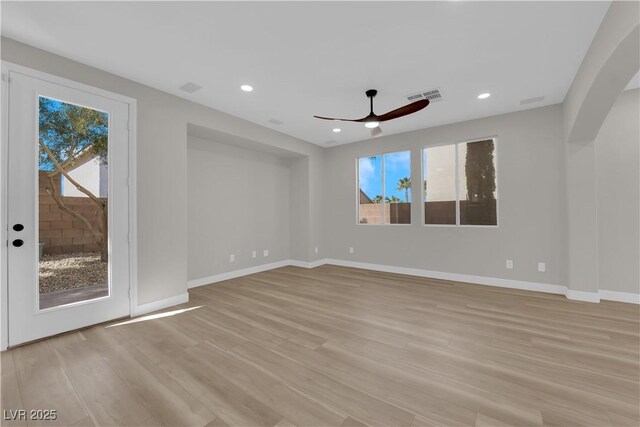 unfurnished room with light wood-style flooring, a healthy amount of sunlight, visible vents, and baseboards