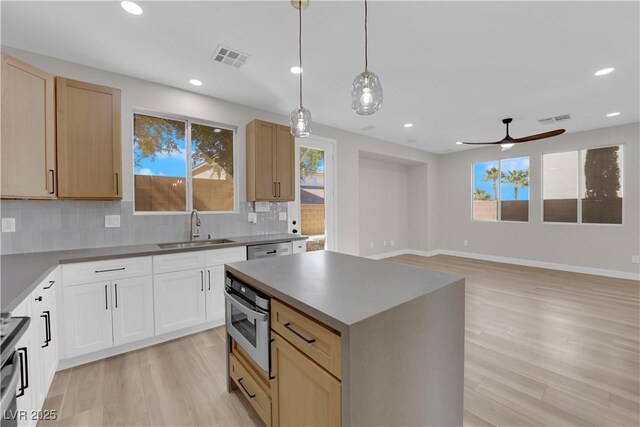 kitchen with tasteful backsplash, visible vents, a sink, light wood-type flooring, and oven