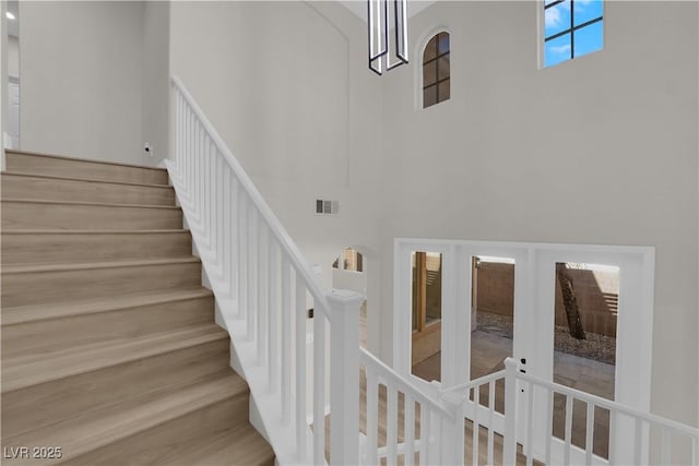 stairway with a high ceiling, visible vents, and french doors