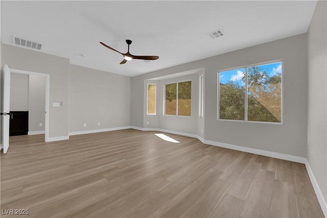 empty room with visible vents, ceiling fan, light wood-style flooring, and baseboards