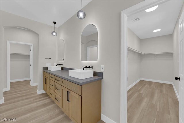 full bath with double vanity, baseboards, a sink, and wood finished floors