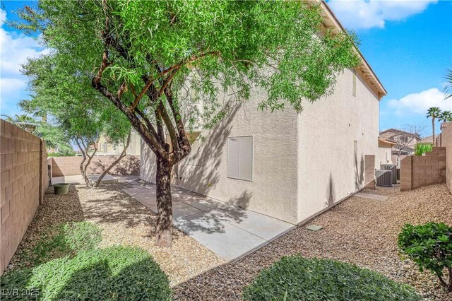 view of home's exterior featuring a patio area, a fenced backyard, central AC, and stucco siding