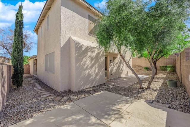 view of property exterior featuring a fenced backyard, a patio, and stucco siding