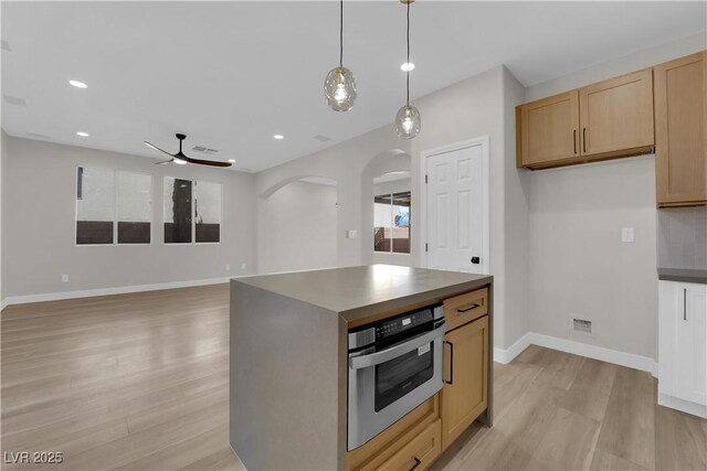 kitchen featuring arched walkways, light wood-style flooring, dark countertops, and stainless steel oven