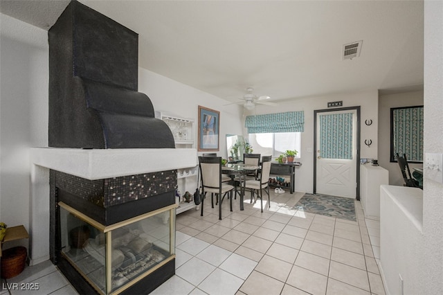 dining space featuring a tiled fireplace, visible vents, and tile patterned floors