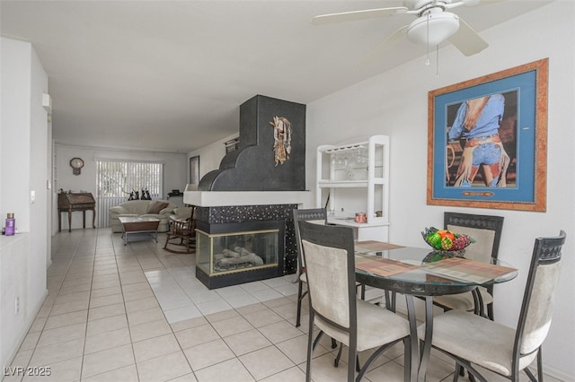 dining area with light tile patterned floors, ceiling fan, and a fireplace