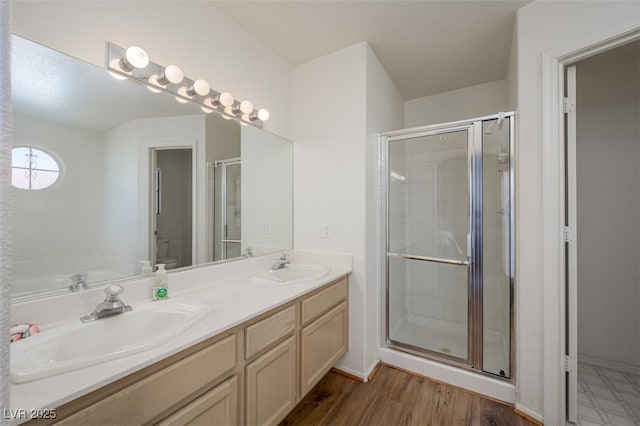 bathroom featuring toilet, a stall shower, double vanity, and a sink