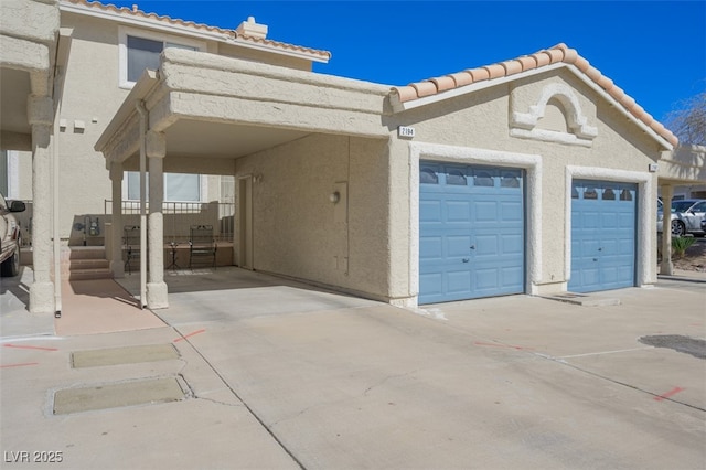 exterior space with an attached garage, a tiled roof, and stucco siding