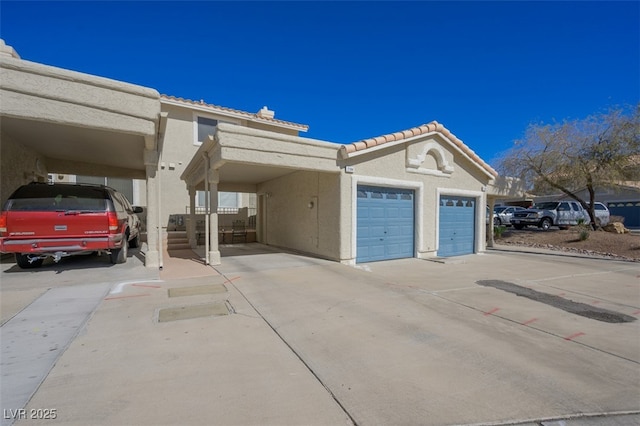 view of front of house featuring a garage, driveway, a tile roof, and stucco siding