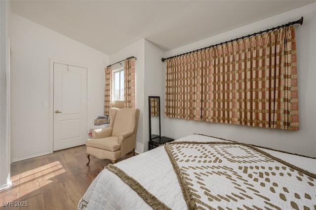 bedroom with vaulted ceiling and wood finished floors