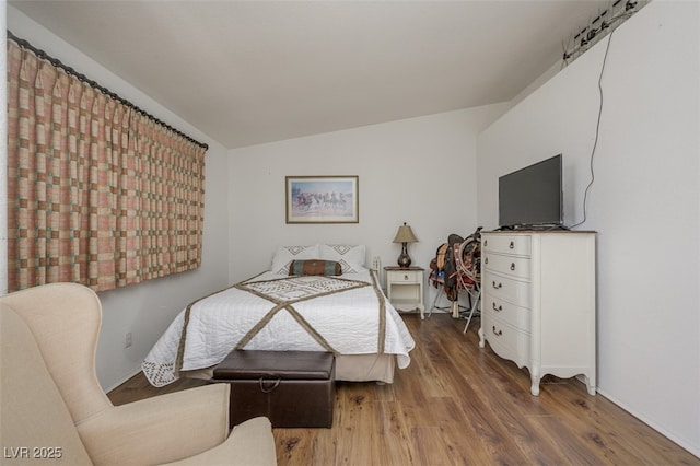 bedroom with vaulted ceiling and wood finished floors