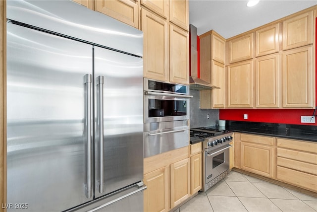 kitchen with light tile patterned floors, high end appliances, dark countertops, light brown cabinets, and a warming drawer