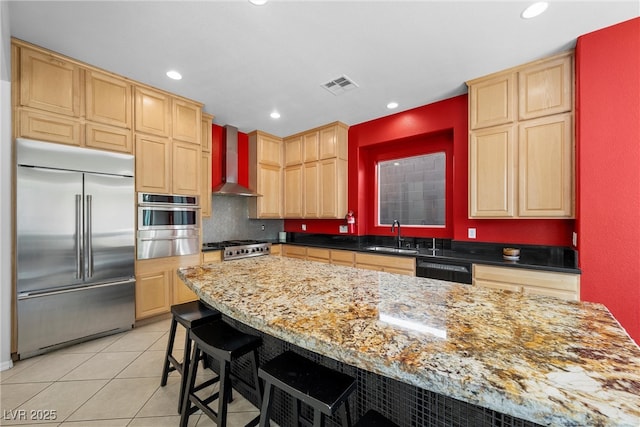 kitchen featuring a sink, visible vents, appliances with stainless steel finishes, wall chimney exhaust hood, and light brown cabinetry