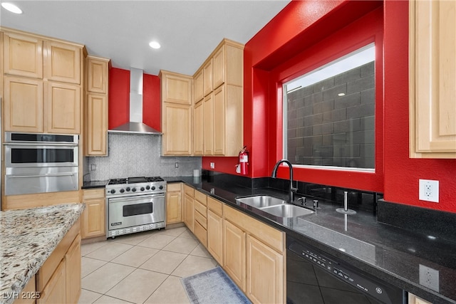 kitchen with stainless steel appliances, light brown cabinetry, wall chimney exhaust hood, and a sink