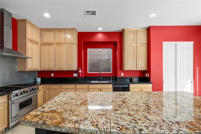 kitchen featuring visible vents, light brown cabinetry, premium range, wall chimney range hood, and a sink