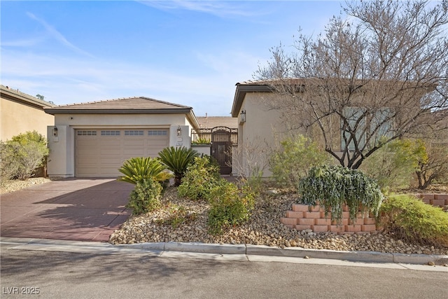 view of front of home with driveway, an attached garage, a gate, and stucco siding