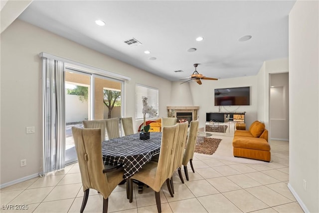 dining space with light tile patterned floors, ceiling fan, recessed lighting, visible vents, and a lit fireplace