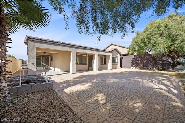 rear view of house with a patio, fence, a garden, and stucco siding