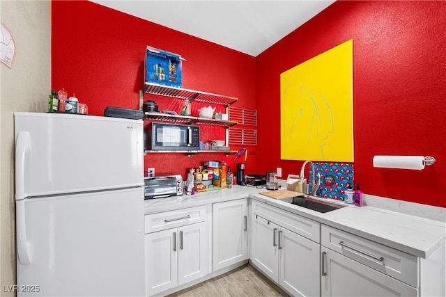 kitchen featuring light wood finished floors, open shelves, freestanding refrigerator, white cabinetry, and black microwave