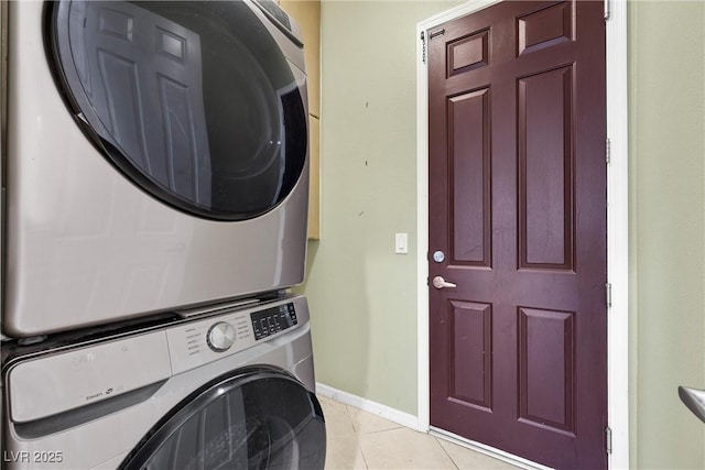 laundry area with light tile patterned floors, stacked washer and dryer, laundry area, and baseboards