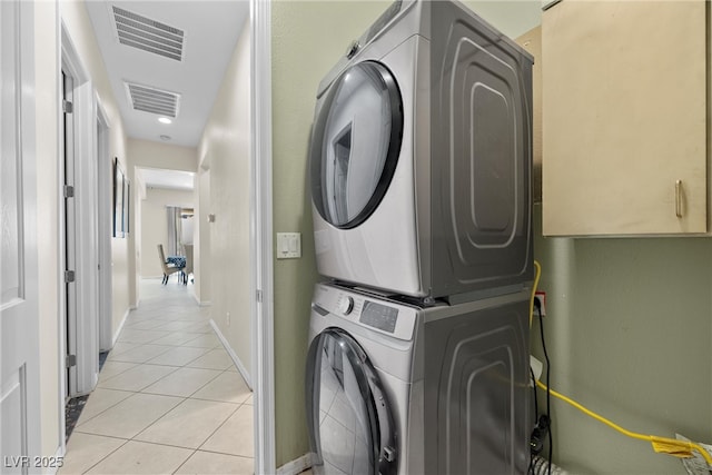 laundry area featuring laundry area, visible vents, stacked washing maching and dryer, and light tile patterned floors