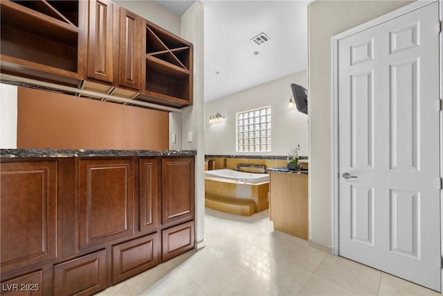 kitchen featuring light tile patterned floors, dark stone counters, visible vents, and open shelves