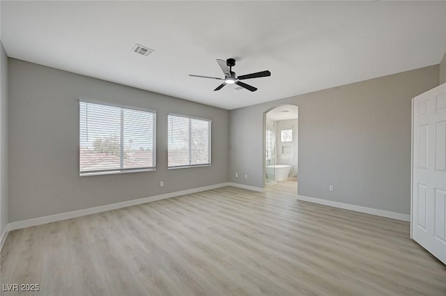 unfurnished room featuring baseboards, visible vents, arched walkways, ceiling fan, and light wood-type flooring