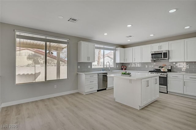 kitchen with stainless steel appliances, light countertops, visible vents, white cabinetry, and light wood-type flooring