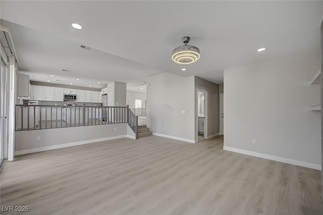 unfurnished living room with recessed lighting, visible vents, light wood-style flooring, and baseboards