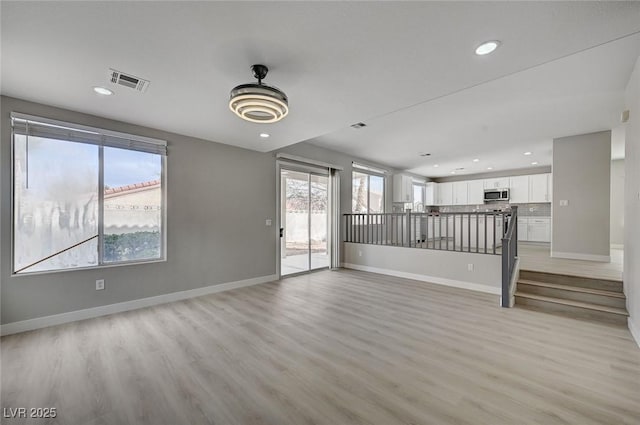 empty room featuring light wood finished floors, baseboards, visible vents, and recessed lighting