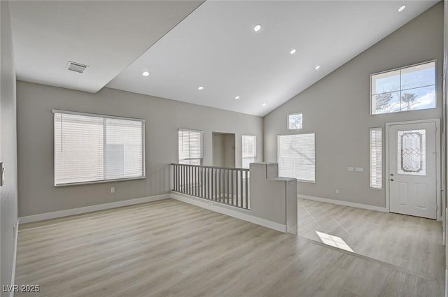 foyer entrance featuring light wood finished floors, recessed lighting, visible vents, high vaulted ceiling, and baseboards